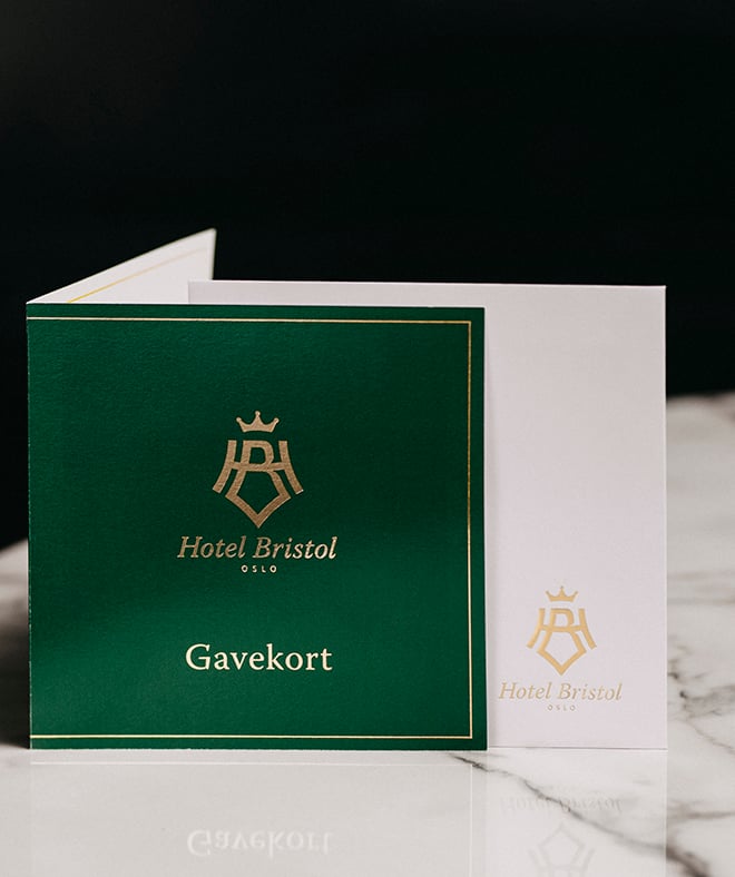 Gavekort med hotellets logo står  under juletre samme med tekopp og sandaler med hotellets logo, og gaver i gullpapir.